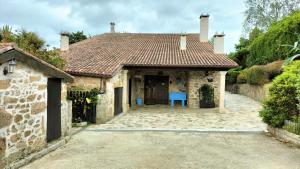 聖徐連代薩利斯的住宿－As Seis Chemineas，房屋设有瓷砖屋顶和蓝色椅子