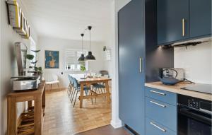 a kitchen and dining room with blue cabinets and a table at 3 Bedroom Lovely Home In Sams in Ballen