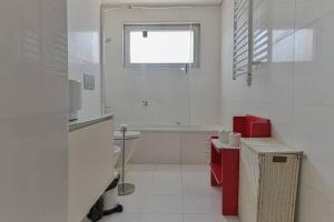 a white bathroom with a red sink and a window at Ola Lisbon - Benfica in Lisbon