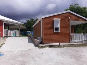 um pequeno edifício castanho com uma janela e um alpendre em Bungalow agéable et confortable, parking securisé em Vieux-Habitants