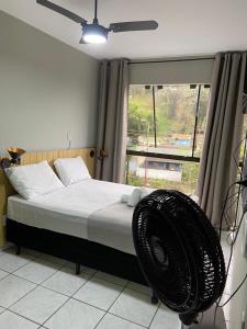 a bedroom with a bed with a fan next to a window at Pousada VSC in São Francisco do Sul