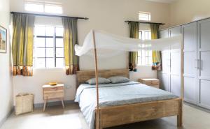 ein Schlafzimmer mit einem Himmelbett in der Unterkunft JINJA HOUSE in Jinja