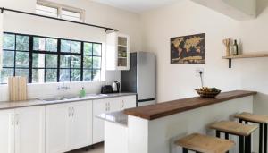 a kitchen with white cabinets and a large window at JINJA HOUSE in Jinja