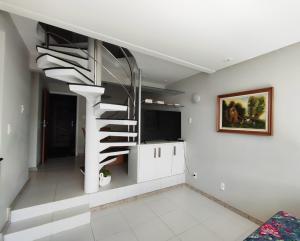 una scala a chiocciola in un soggiorno con televisore di Aluguel temporada em Vilas do Atlantico a 2 minutos da praia a Lauro de Freitas