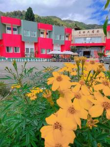 a bunch of yellow flowers in front of a building at Shi Bi Hotel in Gukeng