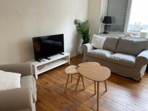 a living room with a couch and a tv and a table at Appartement en coeur de ville 2 personnes in Bort-les-Orgues