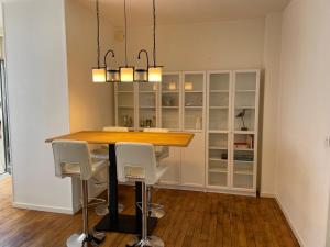 cocina con mesa de madera y armarios blancos en Appartement en coeur de ville 2 personnes, en Bort-les-Orgues