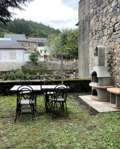 a table and chairs in a yard with a stone wall at Appartement Suzon en coeur de ville 2 personnes in Bort-les-Orgues