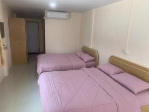 - 2 lits dans une chambre avec des draps roses dans l'établissement บ้านพักณัฐรินีย์, à Sam Phran