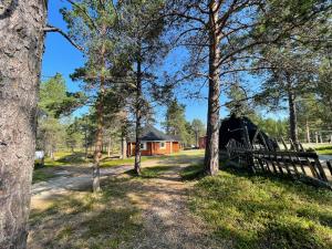 uma cabana na floresta com uma cerca e árvores em Porotila Toini Sanila em Sevettijärvi