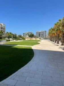 un parque con palmeras y un paseo. en Okeanos Bmarina, en Herzliya