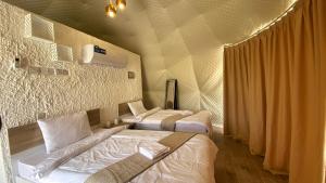 Jabal shams domes في Sa‘ab Banī Khamīs: سريرين في غرفة الفندق مع سريرين مطلة على السرير