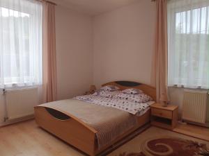 a bedroom with a wooden bed and two windows at MAGNOLIA Duszniki Zdrój in Duszniki Zdrój