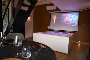 una pantalla de proyección en una habitación con una mesa con copas de vino en Intimate - Private Wellness, en Héron