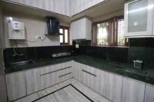 eine Küche mit weißen Schränken und einer grünen Arbeitsplatte in der Unterkunft 4BHK Shruti Home Stay in Varanasi