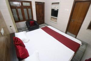 ein Schlafzimmer mit einem großen weißen Bett und einem Stuhl in der Unterkunft 4BHK Shruti Home Stay in Varanasi