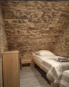 - une chambre avec un lit et un mur en bois dans l'établissement Rajskie wzgórze w Karkonoszach, à Łomnica
