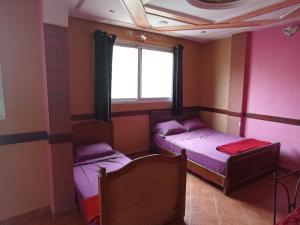 twee bedden in een kamer met een raam bij hotel evasion in Marrakesh