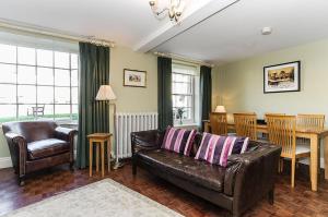 a living room with a leather couch and a table at Wixey House in Chipping Campden