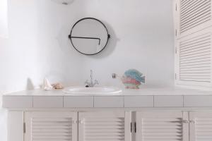 a white bathroom with a sink and a mirror at Villa Unica in Yiannioú