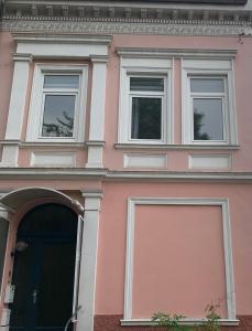a pink building with three windows and a door at Edu Home Bremen in Bremen