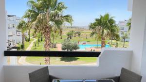 a balcony with a view of a pool and palm trees at Apartamento golf-resort murcia in Murcia