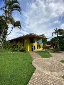 a yellow house with a palm tree in front of it at Ecohotel La Casona Pereira in Pereira