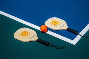 two ping pong paddles with an orange ball on a court at Platinum Yucatan Princess Adults Only - All Inclusive in Playa del Carmen