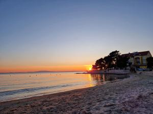 un tramonto sulla spiaggia con una casa sullo sfondo di Villa Petrac - App5 & App5A a Rab