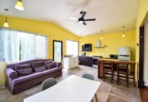 a living room with a purple couch and a kitchen at Cabinas Jacaranda in Puerto Viejo