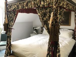 a bedroom with a canopy bed with white sheets at Margaret's Manor in Birchington