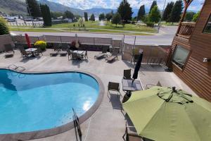a swimming pool with an umbrella and tables and chairs at Lake Chelan View Condo in Downtown near Beach! in Chelan