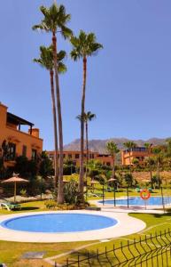 uma grande piscina com palmeiras e um edifício em Bonito apartamento en Marbella con piscina em Marbella