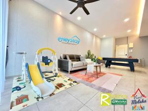 uma sala de estar com um sofá e uma área recreativa em Atlantis Residences Melaka by HeyStay Management em Malaca