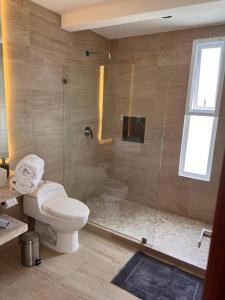 a bathroom with a toilet and a glass shower at Depto en Diamante con Club de Playa Privado in Acapulco +23 photos