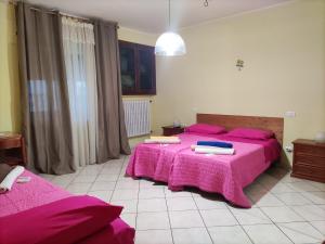 a bedroom with two beds with pink sheets at Bed and Breakfast La Campanula in Vittorito