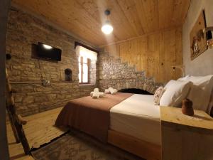 een slaapkamer met een bed en een stenen muur bij Melodia - Harmony Heaven in Gjirokastër