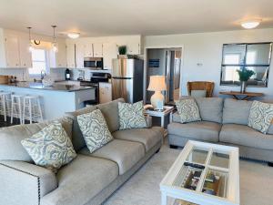 a living room with two couches and a kitchen at Dune Deck North - Duplex in Holden Beach