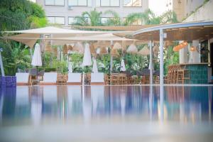 a pool with chairs and umbrellas in a building at Odysseia Hotel Kapetanios in Limassol