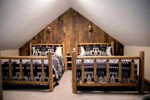 two beds in a bedroom with a wooden wall at Jasper Gates Resort in Jasper