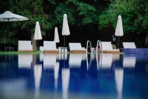 a swimming pool with white chairs and umbrellas at Odysseia Hotel Kapetanios in Limassol