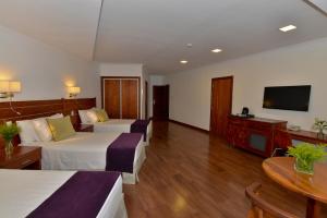 a hotel room with two beds and a flat screen tv at Hotel Saint George in Puerto Iguazú
