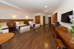 a hotel room with two beds and a flat screen tv at Hotel Saint George in Puerto Iguazú
