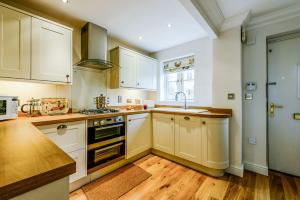 a kitchen with white cabinets and a sink and a stove at Gem Cottage in Chipping Campden