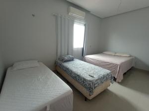 two beds in a small room with a window at Residência em Bairro Nobre in Imperatriz