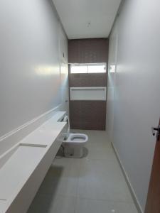 a white bathroom with a toilet and a sink at Residência em Bairro Nobre in Imperatriz
