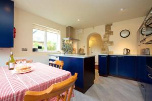 a kitchen with blue cabinets and a table with a tablecloth at Badgers End in Chipping Campden