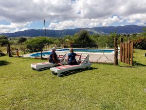 twee mensen op banken voor een zwembad bij cabañas santa catalina in Villa Giardino