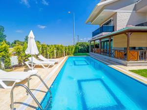 a swimming pool with chairs and a house at Paradise Town Villa Belhamra in Belek