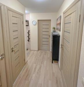 a hallway with two doors and a clock on the wall at Jaukūs, erdvūs, šilti apartamentai in Klaipėda